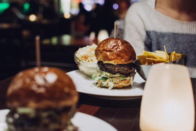 foodiesfeed.com_celebrating-with-a-juicy-beef-burger-in-a-restaurant-scaled-e1650372291220 L'utilisation des QR codes en restauration est une innovation